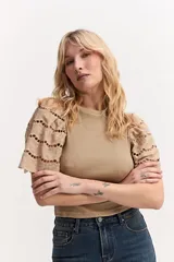 Remera color tostado con cuerpo acanalado y mangas cortas abullonadas con bordados calados.
