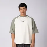 Remera de algodón con mangas raglán color verde militar y cuerpo color crudo, con cuello redondo y diseño estampado en el pecho con el texto 'ART DEPT. VCP'.