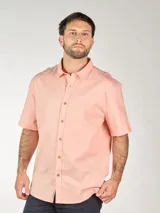 Camisa de lino color beige, de manga corta, con cuello clásico y cierre frontal con botones.