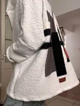 Campera de corderito blanco con capucha, de corte holgado y diseño tipo collage en la espalda con parches geométricos en tonos gris, negro y detalles en color. Incluye etiqueta de marca en la parte inferior trasera.