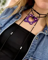 Gargantilla choker con dije de acrílico violeta con forma geométrica y apliques de strass. El collar es de tiento negro con cuentas plateadas.