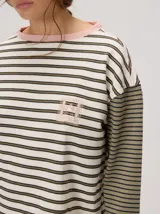 Remera manga larga de corte oversize y cuello redondo, con diseño a rayas horizontales en tonos claros y verde militar, y detalle de bordado frontal.