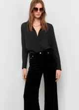 Jeans wide leg de terciopelo color negro, tiro medio, con cierre de botón y cremallera, trabillas y diseño de cinco bolsillos.