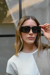 Lentes de sol con montura gruesa de forma cuadrada y ligeramente redondeada, en color carey oscuro. Los cristales son oscuros.