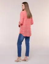 Blusa turquesa de silueta suelta confeccionada en tejido liviano, con escote en V, pequeña cartera frontal con botones decorativos y mangas 3/4 con presilla para arremangar. Presenta patrón estampado geométrico tipo tie-dye y ruedo curvo.
