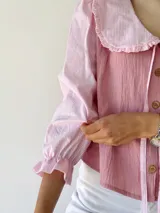 Camisa rosa con mangas 3/4 a rayas y cuello babero con volados.