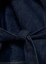 Abrigo corto estilo chaqueta de jean, confeccionado en algodón denim azul oscuro. Presenta cuello con solapas, cierre frontal, trabillas en los hombros y mangas largas con trabillas ajustables.