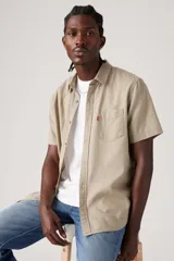 Camisa de manga corta color beige con bolsillo en el pecho y cierre con botones.