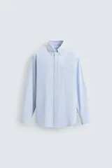 Camisa de corte regular fit confeccionada en tejido de algodón con diseño de rayas verticales finas. Presenta cuello abotonado, manga larga con puños abotonados, bolsillo plastrón en el pecho y cierre frontal con botones.