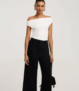 Pantalón de jean modelo wide leg cropped con cintura alta y sastre. Presenta costuras verticales frontales, bolsillos laterales y cierre delantero tradicional.