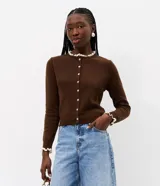 Cardigan de punto marrón de manga larga, con cierre frontal de botones y detalles de encaje blanco en el cuello redondo y los puños.
