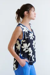 Top sin mangas de corte holgado con escote en V, estampado floral en blanco sobre fondo azul marino. Presenta vivos de color azul eléctrico en el escote y sisas.