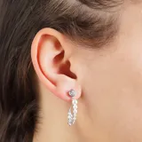 Aros colgantes plateados con un cristal redondo en la parte superior, seguidos de una línea vertical de perlas y dos hojas plateadas con pequeños cristales.