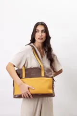 Cartera de hombro tipo portafolio confeccionada en cuero vacuno, con diseño estructurado que combina marrón liso y un panel frontal en cuero texturizado color mostaza. Posee doble asa larga y cierre superior.