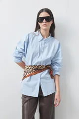 Camisa de algodón color celeste, de corte relajado y silueta clásica, con cuello camisero, cierre frontal de botones y mangas largas.