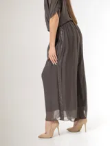 Pantalón de seda italiana con forro de viscosa elastizada, de corte holgado y diseño fluido, con detalles de paillettes en los costados y cintura elastizada.