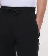 Pantalón jogger deportivo de corte ajustado, con cintura elástica y cordón de ajuste. Cuenta con bolsillos laterales con cierre y puños elásticos en el bajo. Diseño liso en color negro.