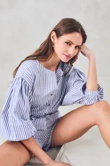 Camisa celeste a rayas verticales blancas, de corte holgado y mangas 3/4 abullonadas.