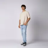 Remera oversize de lino entramado color blanco off-white, con cuello redondo, mangas cortas de hombro caído y etiqueta aplicada en el borde inferior.