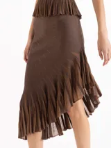 Pollera midi de tejido plisado color marrón, con diseño asimétrico y ruedo con volados.