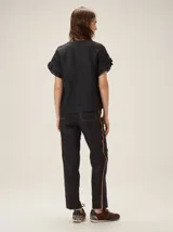 Blusa de lino color crudo, con cuello redondo y mangas cortas adornadas con volados dobles.