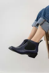 Botín negro de cuero con elásticos laterales, taco bajo y tirador trasero.