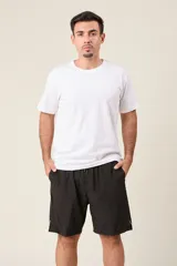 Bermuda deportiva de nylon color gris, de corte suelto, con cintura elástica y cordón de ajuste. Cuenta con detalles de líneas negras en los costados y bolsillos laterales con cierre.