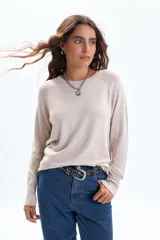 Buzo de punto básico color beige, con cuello redondo y mangas largas tipo ranglan.