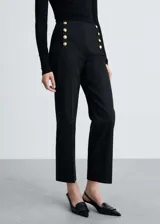 Pantalón de tiro medio y corte recto con diseño crop. Presenta detalles de botones dorados estilo joya en la parte frontal y cierre oculto con cremallera y gancho.