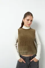 Chaleco de punto color crema con cuello alto y diseño tramado vertical.