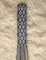 Faja de algodón tejida a mano en telar, de diseño firme y trama apretada, con patrón geométrico en tonos azul y beige, y terminación de flecos en los extremos.