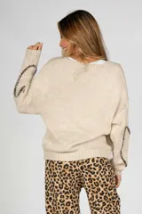 Saco tejido de punto color beige, de corte holgado, con cuello en V y cierre frontal con lazos de tela estampada de leopardo.