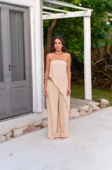 Pantalón de corte amplio y tiro medio, confeccionado en tela crepe color beige, con diseño fluido y holgado.