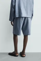 Bermuda relaxed fit confeccionada en lino color celeste, con bolsillos laterales, bolsillos traseros de vivo y cierre frontal con cremallera y botón.