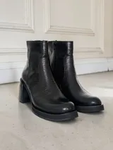Bota corta de cuero negro con textura tipo reptil, taco cuadrado y plataforma. Cuenta con cierre lateral interno.