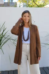 Saco abierto tipo cárdigan de punto en color chocolate, con diseño de corte recto, mangas largas y bolsillos frontales aplicados.