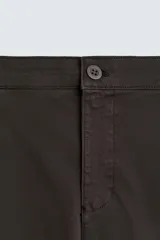 Pantalón chino de corte ajustado, color beige, con bolsillos laterales y bolsillos traseros de vivo. Cuenta con cierre frontal de cremallera y botón.