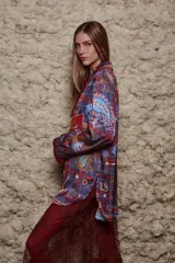 Camisa holgada con estampado geométrico en tonos azules, rojos y marrones. Tiene cuello solapa, mangas largas y cierre abotonado.