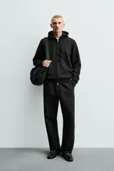 Pantalón jogger de corte regular fit y color negro, confeccionado en tejido compacto de algodón con interior de rizo. Cuenta con cintura elástica, bolsillos frontales y un bolsillo trasero de doble vivo.
