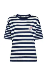 Remera de manga corta con diseño a rayas horizontales en azul marino y blanco, confeccionada en algodón. Presenta un pequeño bordado de hongos en el pecho y cuello redondo.