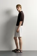 Bermuda de lino negro de corte relaxed fit, con cintura elástica ajustable mediante cordón y bolsillos frontales.