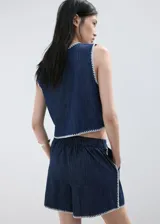 Short de denim azul oscuro de tiro alto, con bolsillos y detalle de bordado blanco en el borde inferior.