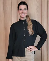 Camisa negra de manga larga con cuello alto tipo mao con volados, cierre frontal con doble botonadura y costuras a la vista en contraste. Presenta puños con volados y un diseño de corte recto.