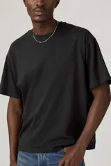 Remera negra de corte cuadrado y holgado, con cuello redondo y mangas cortas.