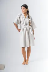 Bata kimono corta color beige, confeccionada en tela waffle de algodón. Tiene mangas al codo, lazo de ajuste en la cintura y detalle de vivo en la solapa.