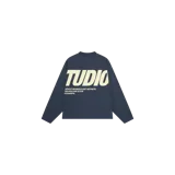 Remera manga larga azul marino con estampado gráfico en la espalda con la palabra 'STUDIO' y texto descriptivo en tono beige.