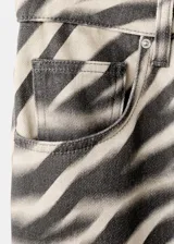 Jeans de corte wide leg con estampado animal print tipo cebra en tonos beige y negro, tiro medio y diseño de cinco bolsillos.
