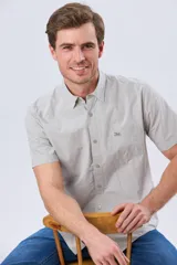 Camisa de manga corta de algodón, con cuello camisero, cierre frontal con botones y un bolsillo aplicado en el pecho con detalle bordado.