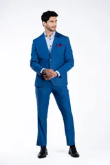 Traje de dos piezas compuesto por saco y pantalón de vestir en color azul brillante. El saco presenta solapas clásicas, cierre frontal de dos botones y bolsillos con solapa. El pantalón es de corte recto y tiro medio.