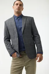 Blazer de corte sastre en color gris con estampado de cuadros en tonos azules. Presenta cierre frontal de dos botones, solapas clásicas y bolsillos laterales con solapa.